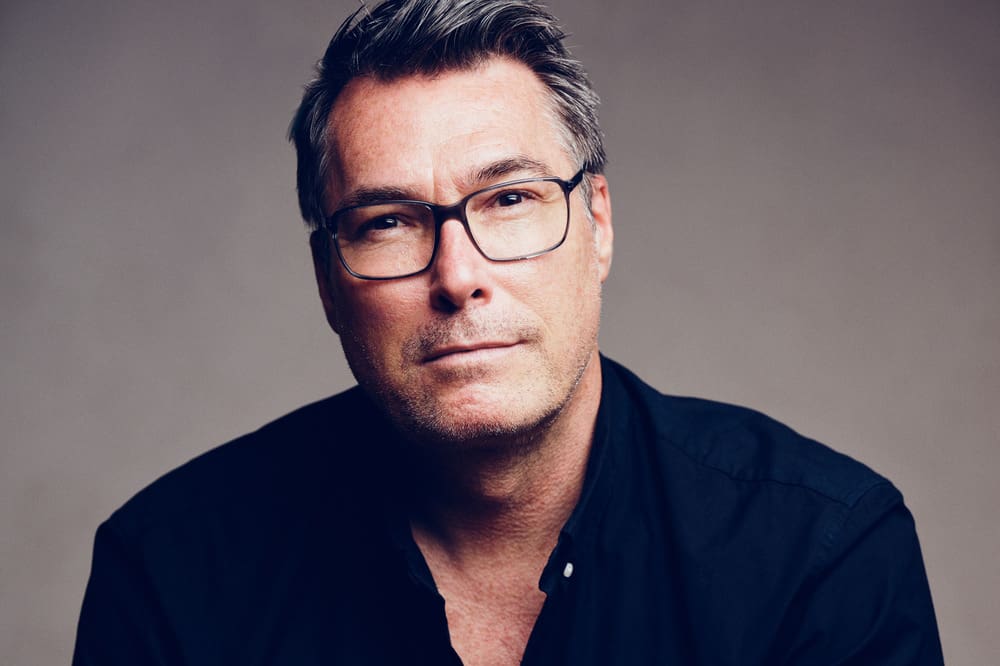 A man with glasses and grey hair wearing a black shirt.