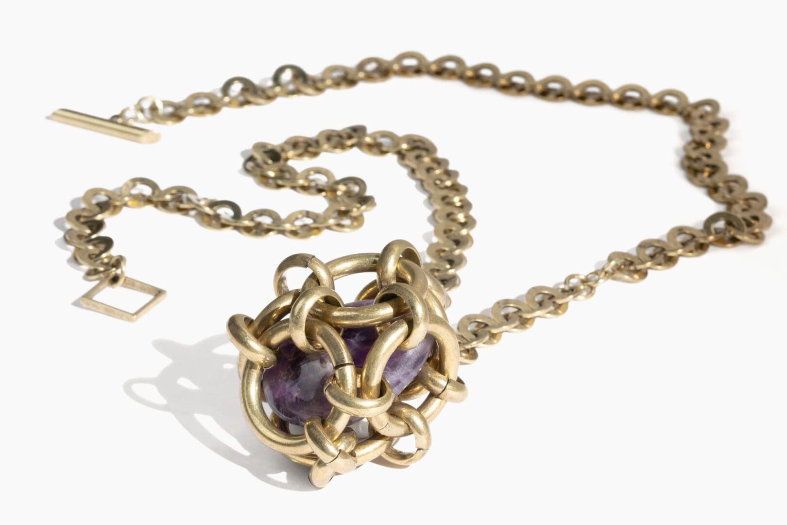 A chain link necklace with a purple stone in the center.