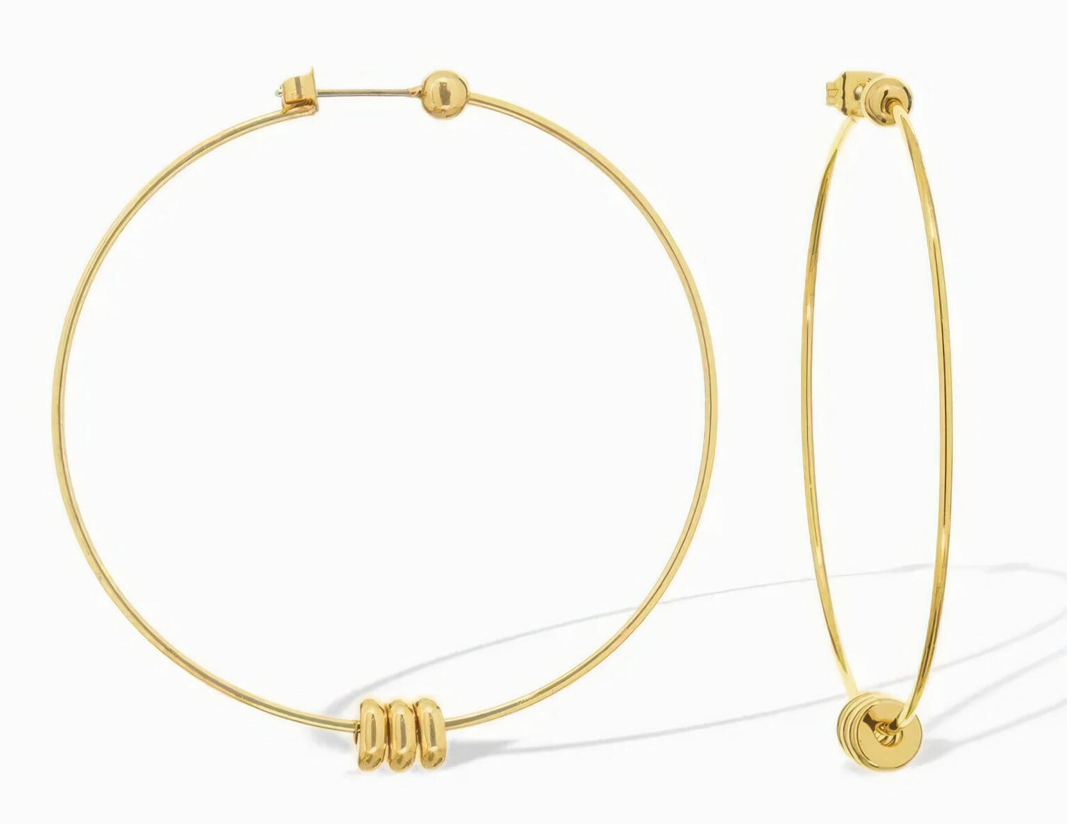 A pair of gold hoop earrings with three small beads.