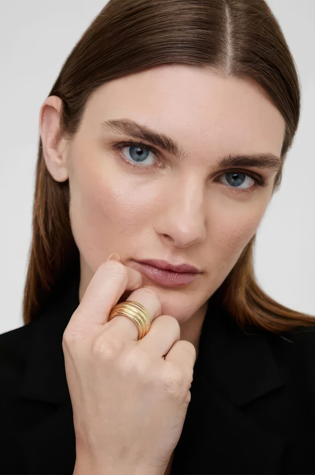 A woman with blue eyes and brown hair wearing a black jacket.