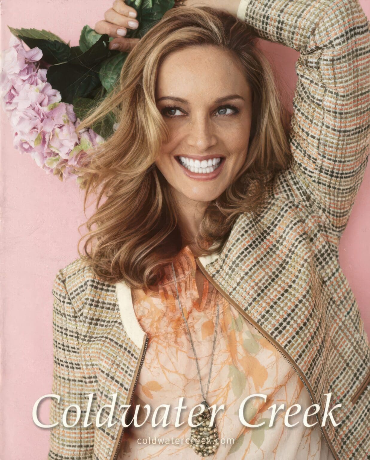 A woman in a jacket and tie holding her arms up.