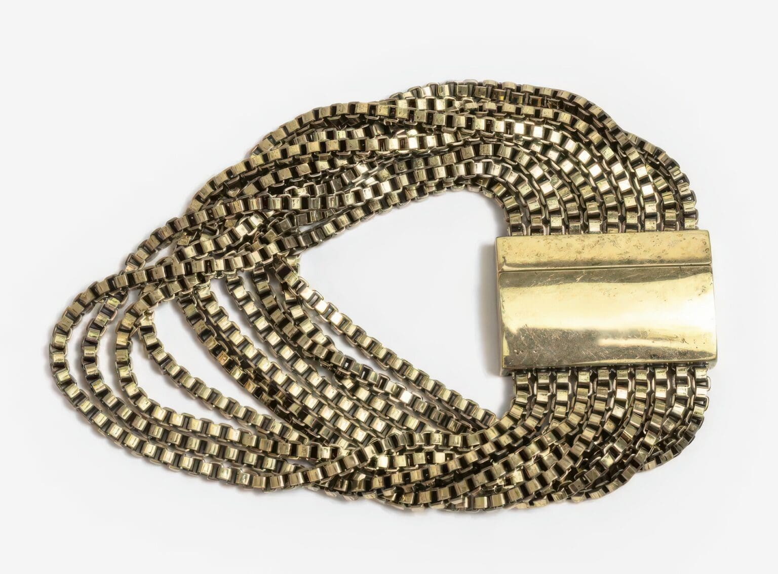 A close up of a chain bracelet with a gold bar