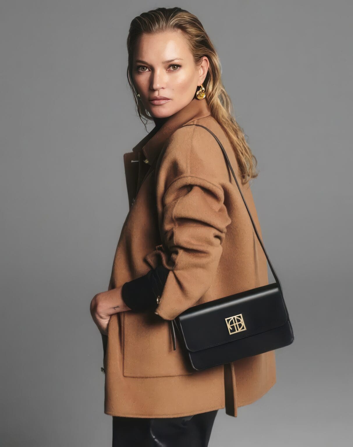 A woman in a brown coat holding a black purse.