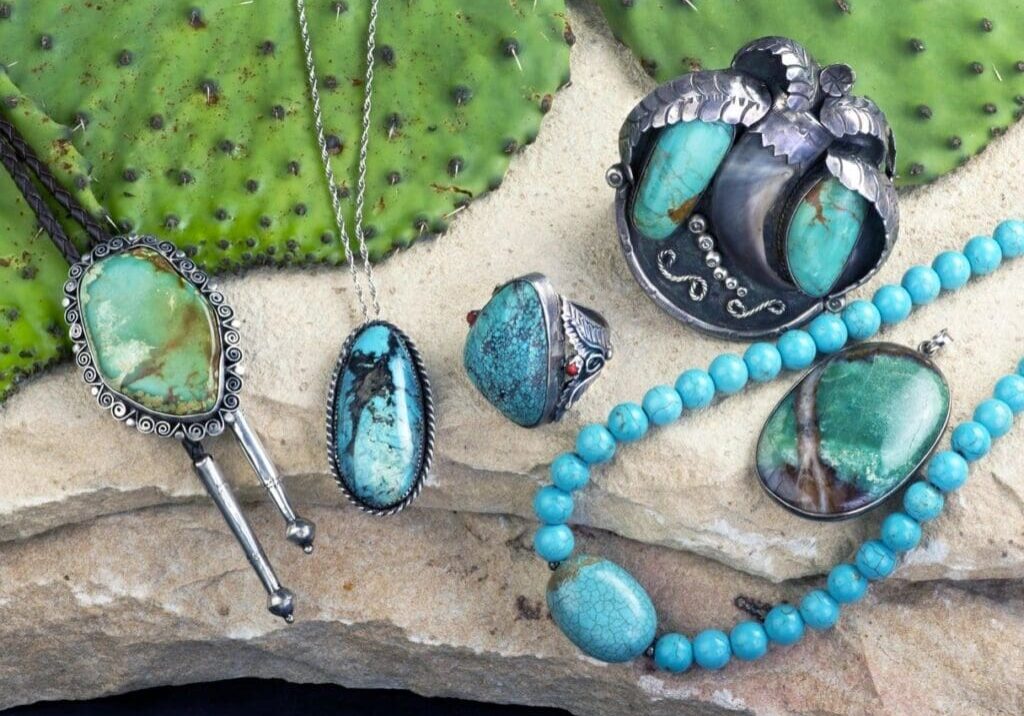 A collection of turquoise jewelry on a cactus.